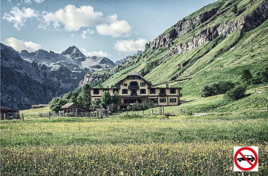 una casa en un campo con montañas al fondo en Hotel Fex, en Sils-Maria
