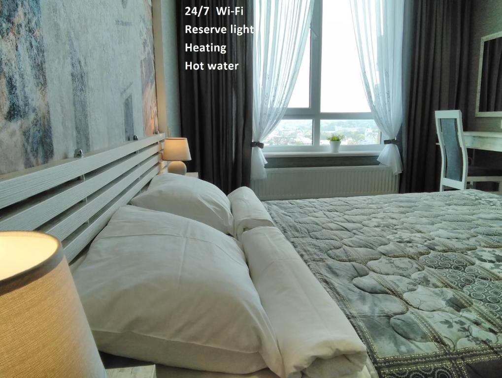a bedroom with a bed with white pillows and a window at Panorama Lviv in Lviv