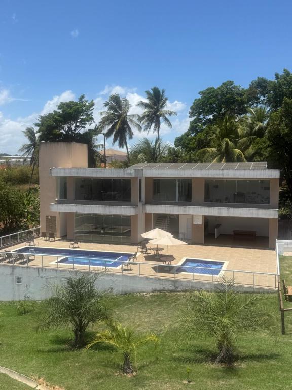a large building with a swimming pool and palm trees at Casa 2 quarto em condomínio in Camaçari