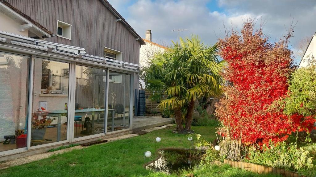 a garden with a house and a tree with red leaves at Chez Uber in Niort