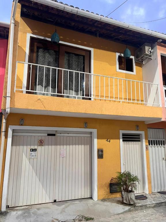 a yellow house with white doors and a balcony at Casa Dourada PIPA RN - Sobrado 2 quartos in Pipa