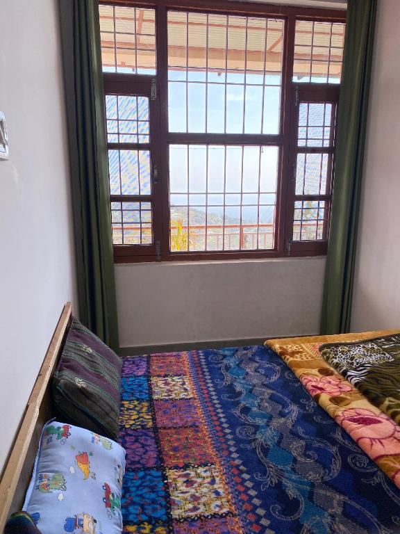 a bedroom with a bed with a rug and windows at Nagwal Hotel in Dharamshala