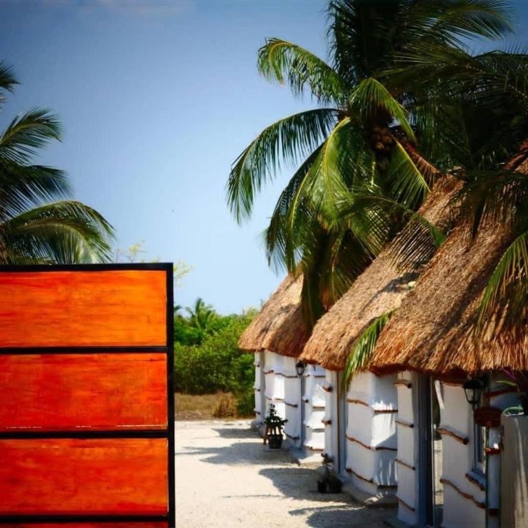 a row of huts with palm trees in the background at Cabañas Cinco Elementos in Celestún
