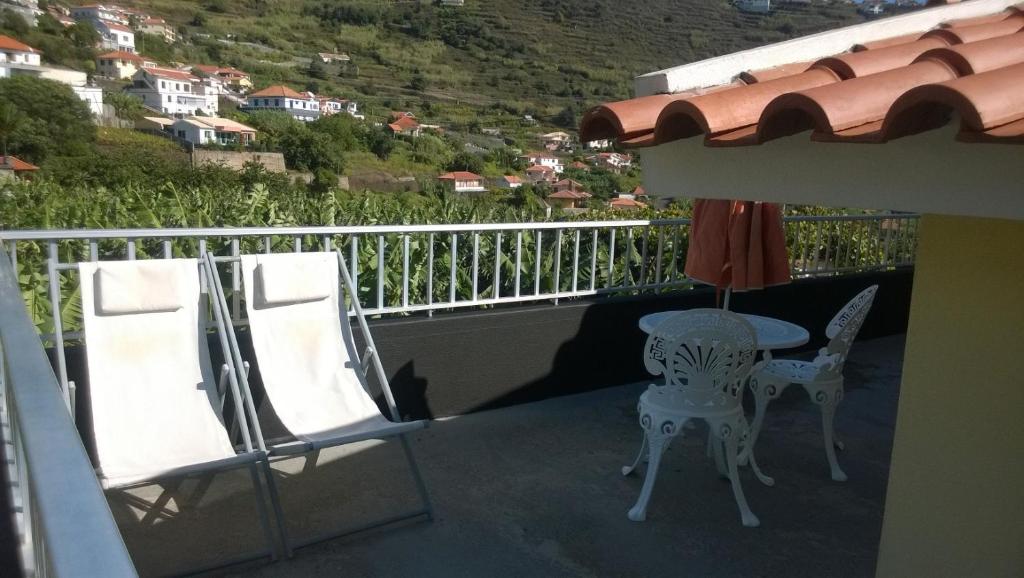 a balcony with two chairs and a table and an umbrella at Apartamento Teixeira 2 in Arco da Calheta
