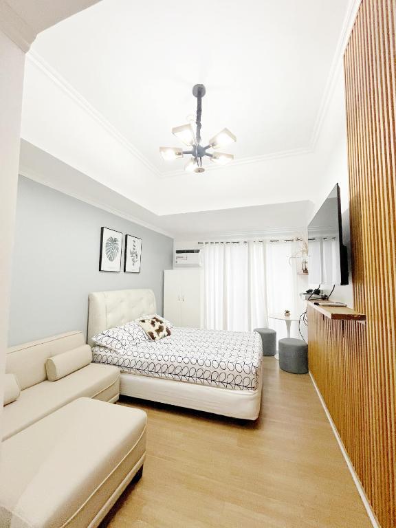a white bedroom with a bed and a couch at Best 10th floor Condo Studio at The Loop Limketkai Center Lucky 4 in Cagayan de Oro