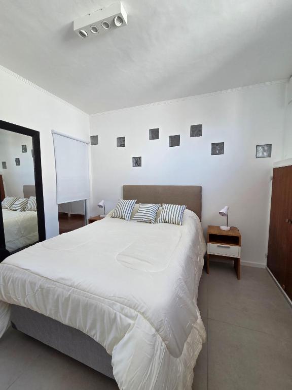 a white bedroom with a large bed and a mirror at Espacio 43 Terminal in La Plata