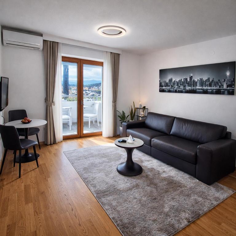 a living room with a black couch and a table at Luxury Apartment-Aurora 33 Free Parking City Center in Podgorica