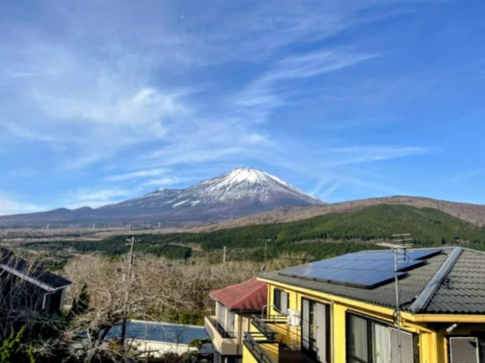 a snow covered mountain in the distance with a house at Fuji Hike Stay in Oyama