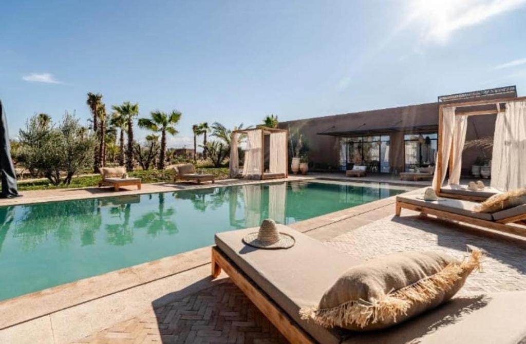 a swimming pool with a bed next to a building at villa Bohème Chic in Had Abdallah Rhiat