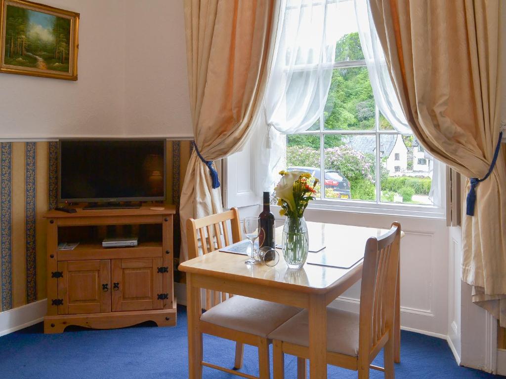 a dining room table with a vase of flowers on it at Rosecraddoc Manor - Natalie Jane in Saint Cleer