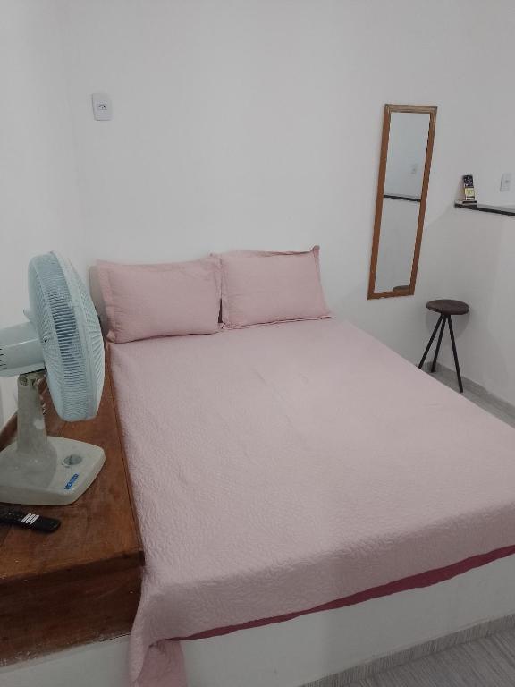 a bedroom with a bed with a fan and a mirror at Vila Bárbara superior in Araruama