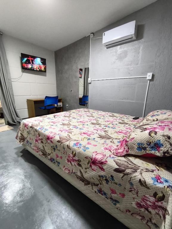 a bedroom with a bed with a floral comforter at Lar Doce Lar Realizando Sono 4 !! in Arcos