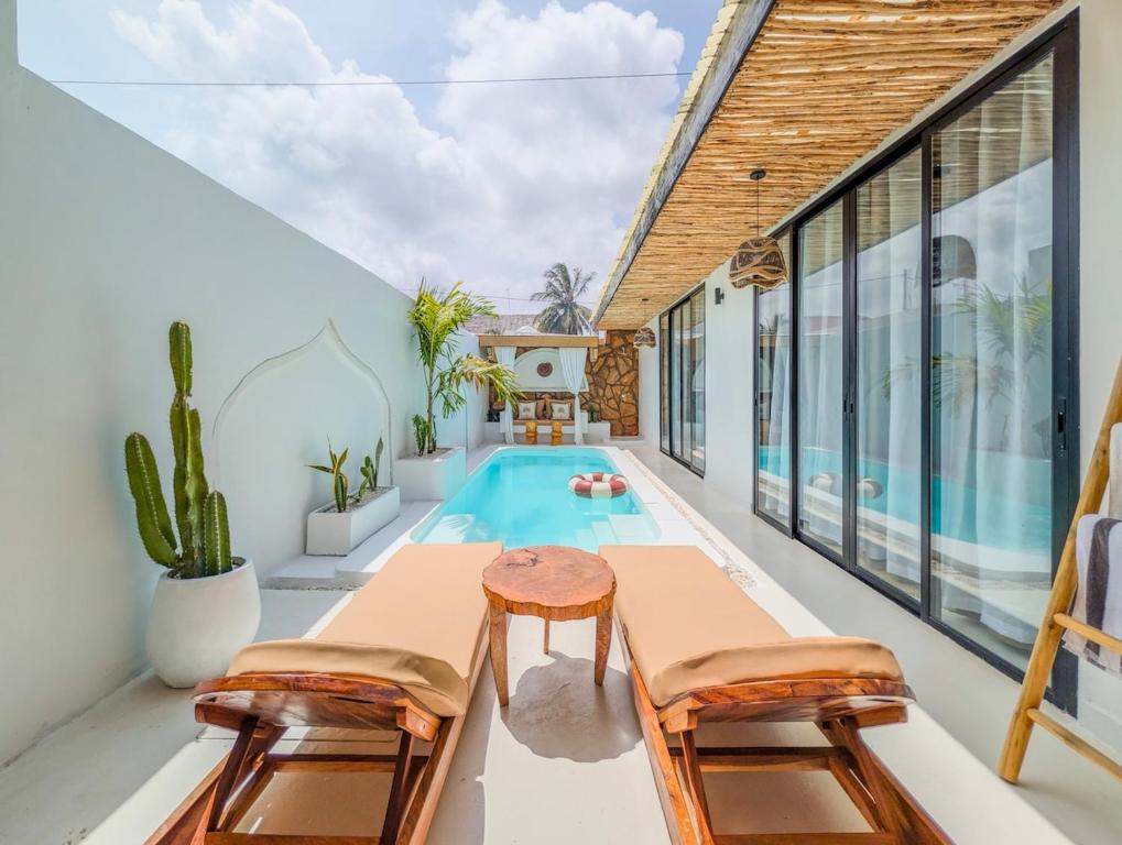 a swimming pool in a house with two chairs and a table at Marram Villas 2 Prime Location in Paje