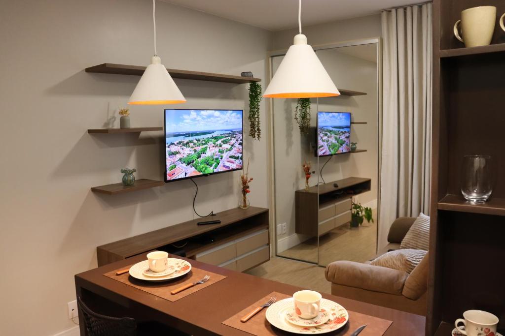 a living room with a table and a tv on a wall at Studio no Sudoeste, vista da 1ª Avenida, tudo a pé in Brasília