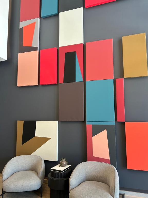 a room with two chairs and a wall with colorful paintings at Las Condes Avenida in Santiago
