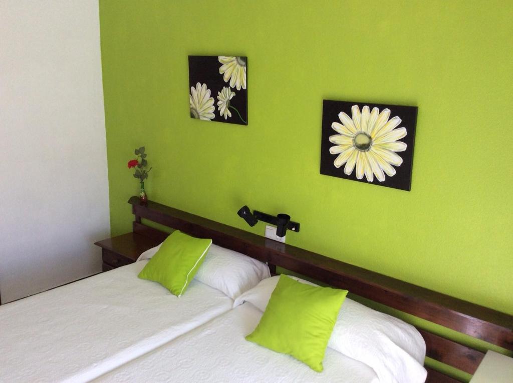 a bed with two pillows and a picture on the wall at Pensión K-Hito in Santiago de la Ribera