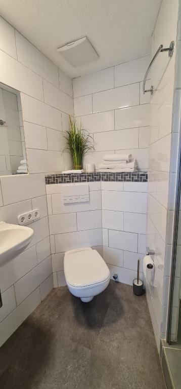 a white bathroom with a toilet and a sink at Pension am Bach good Schlafi in Fuldatal