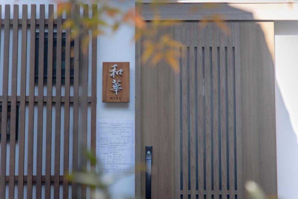 a wooden door with a sign on a wall at 三十三 和華waka in Kyoto