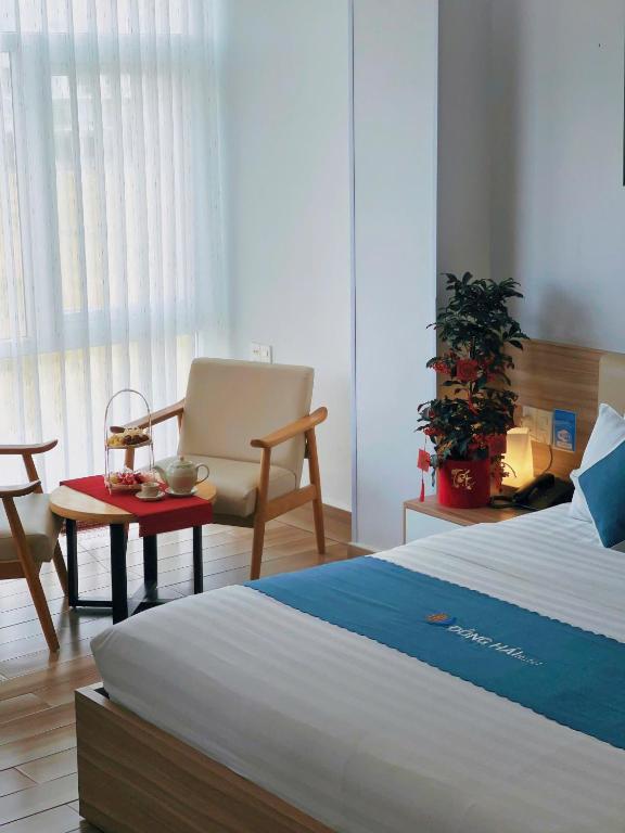 a bedroom with a bed and a chair and a table at Dong Hai Hotel _ Rach Gia in Rạch Giá