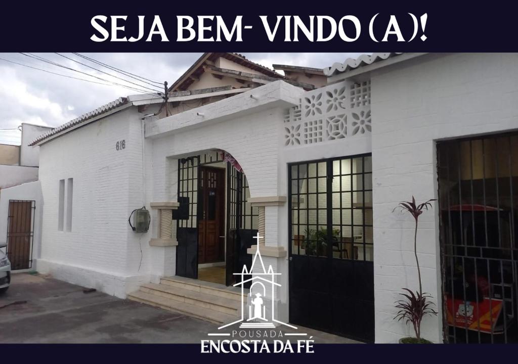 a white house with a black door and a sign at Pousada Encosta da Fé - Unidade Centro in Juazeiro do Norte