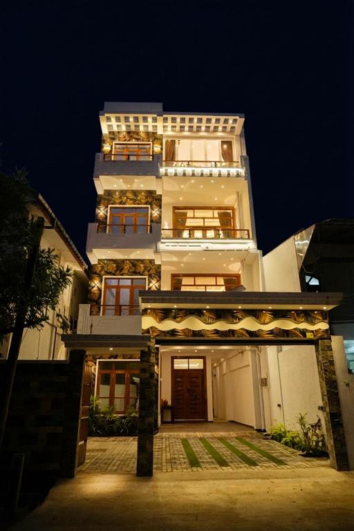 a tall white building at night with a lit up at Trinco Beachfront Villas AJS in Trincomalee