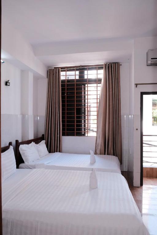 two beds in a bedroom with a large window at 5H homestay & Motorbikes For Rent in Hue