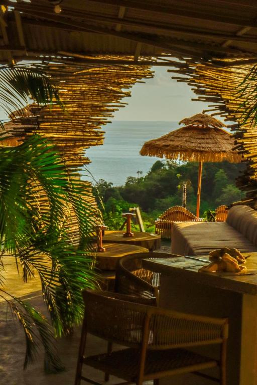 a restaurant with tables and chairs and an umbrella at Dar Lamia Boutique Hotel - Adults Only in Manuel Antonio
