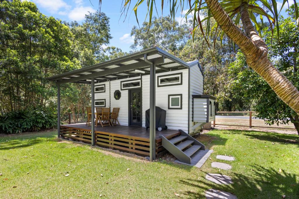 a tiny house with a deck in a yard at Rural Oasis - Tiny Home 2BR Cabin & Outdoor Firepit Experience in Palmwoods