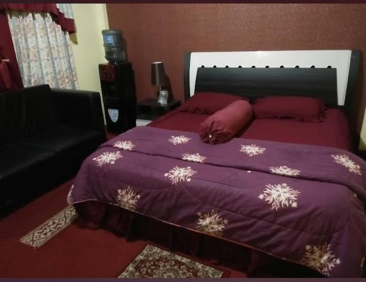 a bedroom with a large bed with a purple blanket at Hotel Raudah Kapuas in Kualakapuas