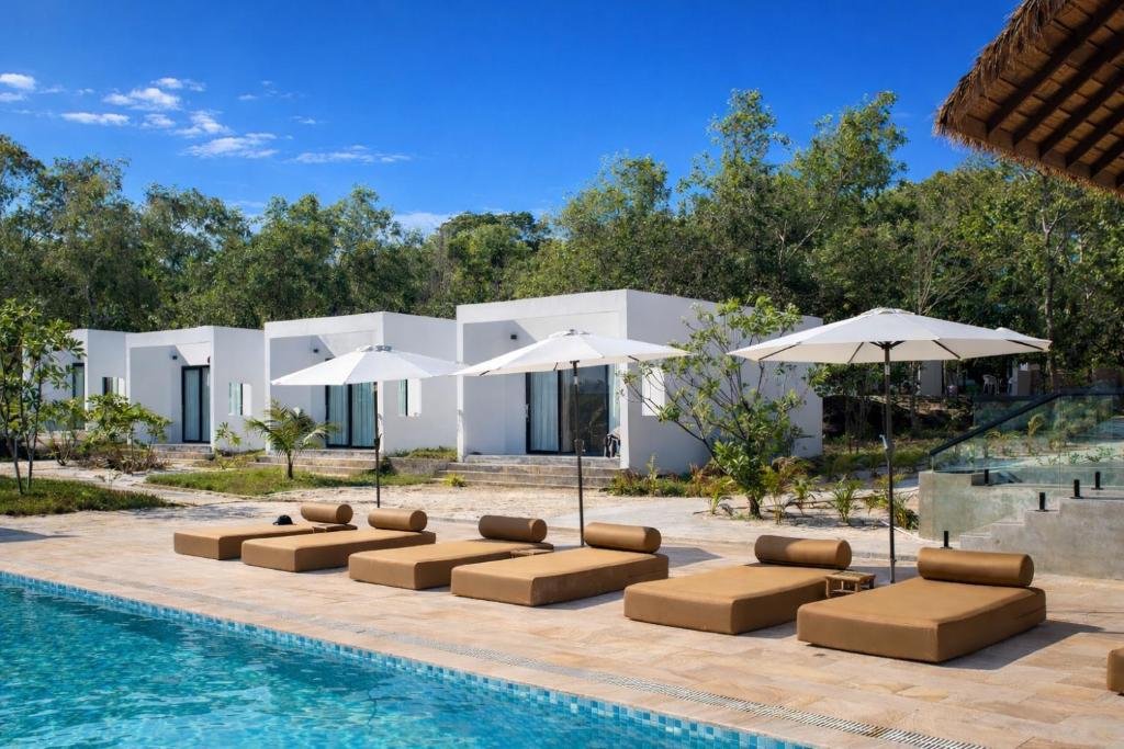 a villa with a swimming pool with lounge chairs and umbrellas at Le Baoli Koh Rong in Phumĭ Kaôh Rŏng