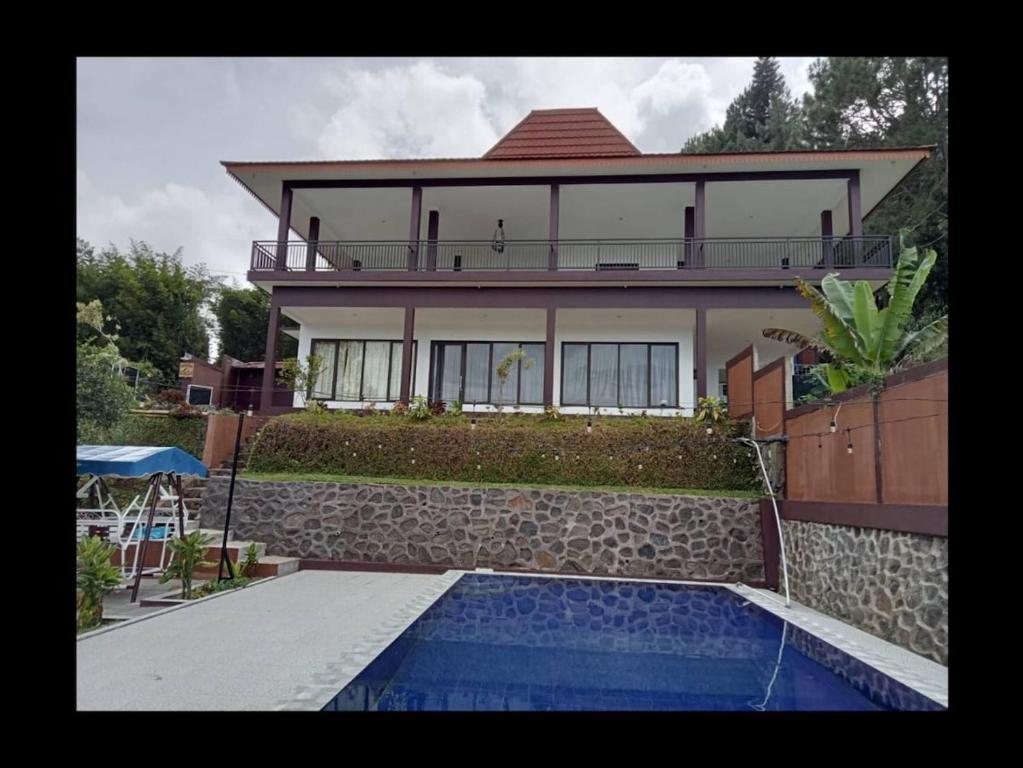 a house with a swimming pool in front of a house at Villa Brown Cisarua in Paragajen