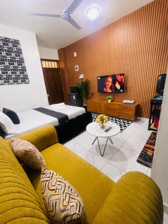 a living room with a couch and a bed and a tv at Mo Homes studio in Mombasa