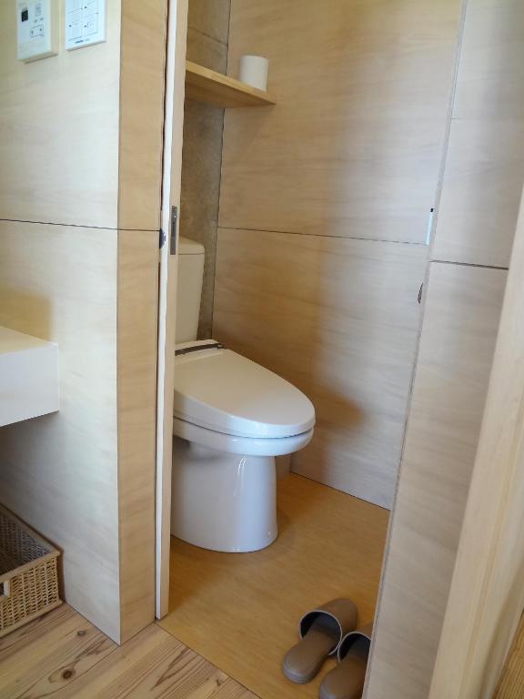 a small bathroom with a toilet and a pair of shoes at Asahinoyado Shidakaji in Nanjo