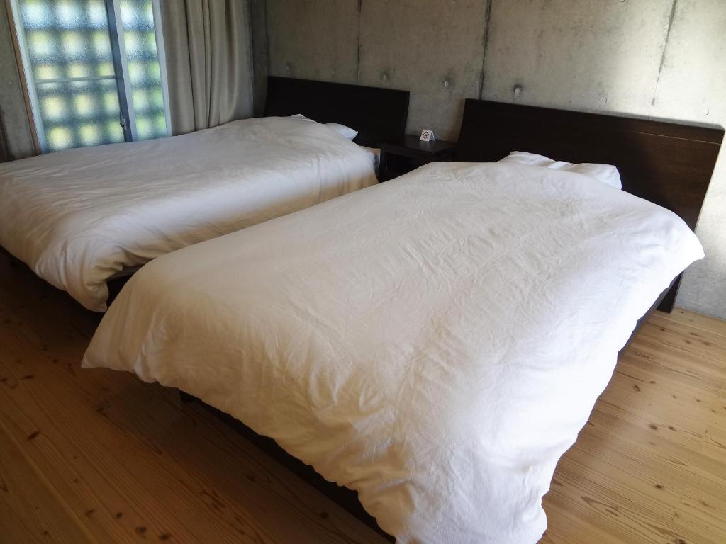 two beds with white sheets in a bedroom at Asahinoyado Shidakaji in Nanjo