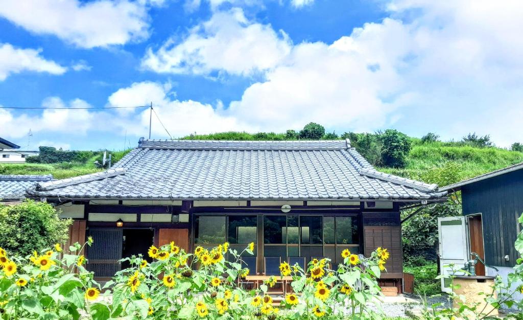 a house with sunflowers in front of it at 古民家のこのこ in Tanabe
