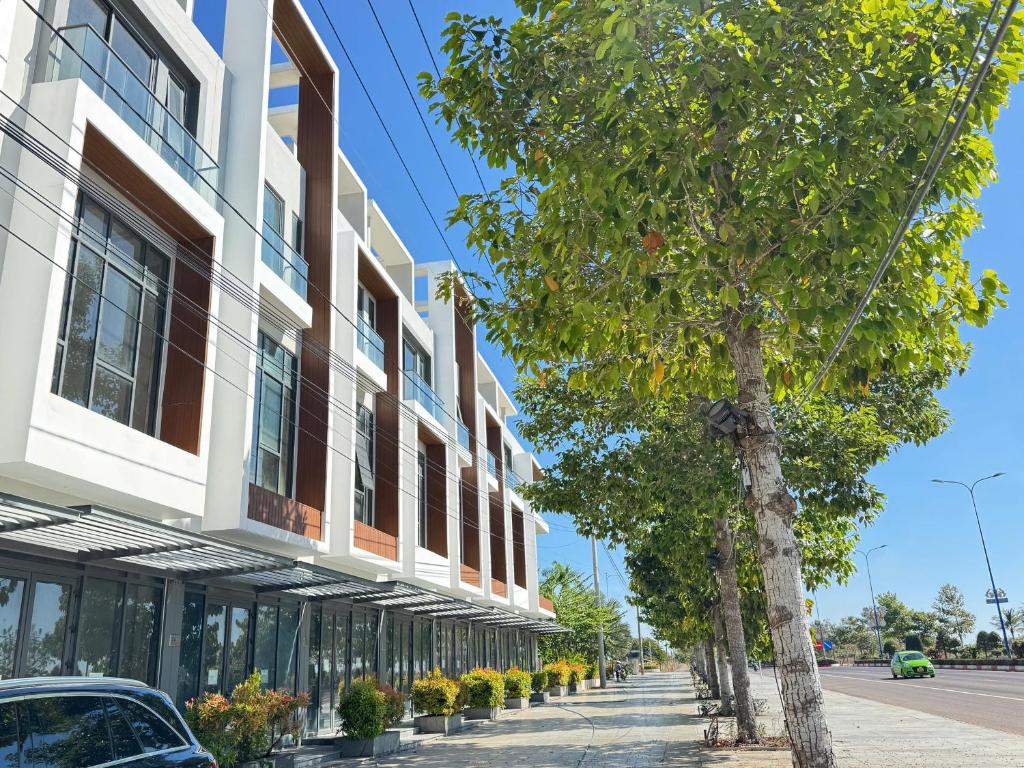 a building with trees next to a street at Homestay Tứ Thiên in Phan Thiet
