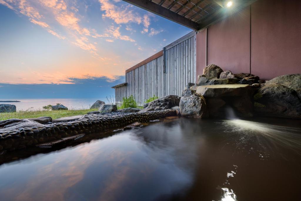 a body of water in front of a building at Hotel Grand Mer Sankaiso in Ajigasawa