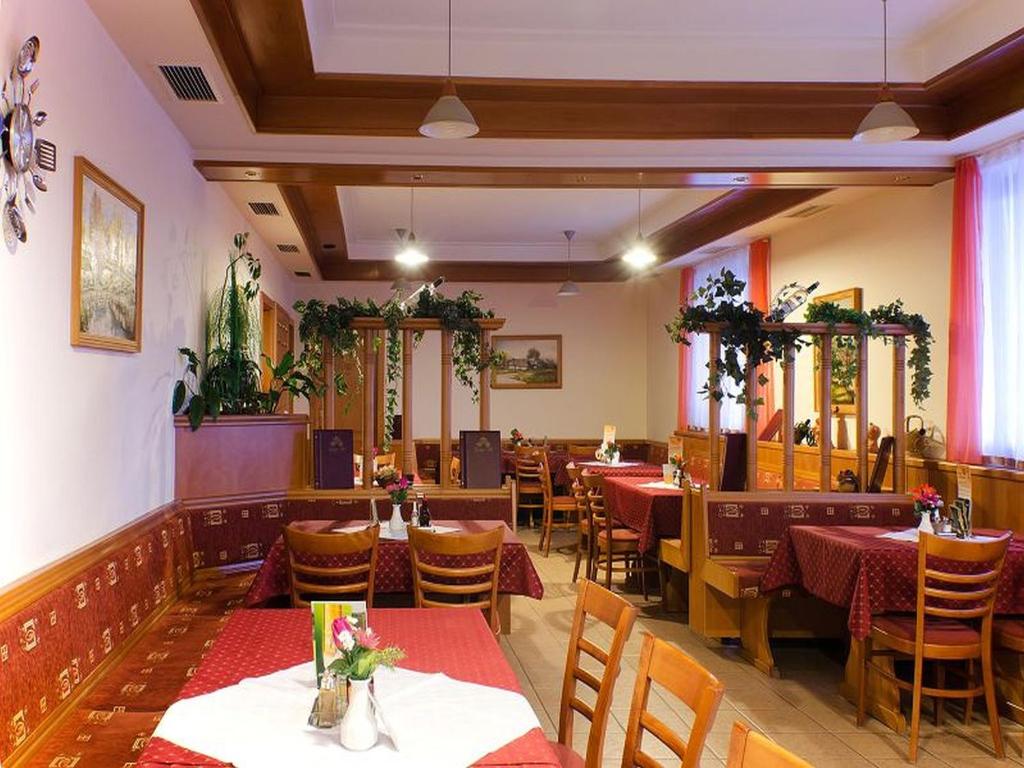 um restaurante com mesas e cadeiras num quarto em Denis Panzió és Étterem em Lenti
