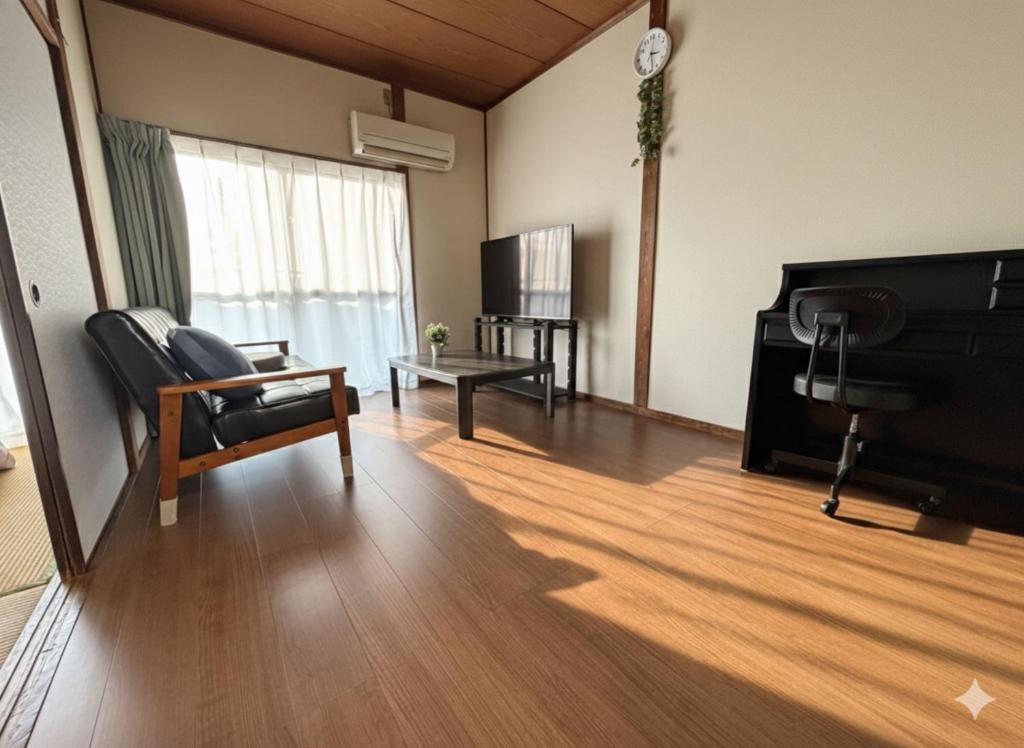 a living room with a chair and a piano at Omuta Cozy Stay in Ōmuta