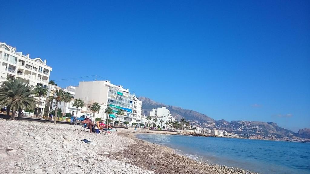 a group of people sitting on a beach next to the water at Apartamentos La Mar in Altea
