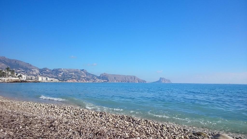 a beach with blue water and mountains in the background at Apartamentos La Mar in Altea