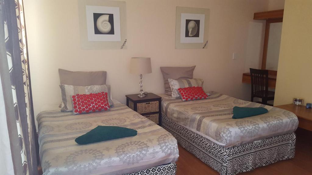 two twin beds in a room with a lamp at Natalie Guesthouse in Bloubergstrand