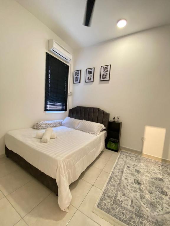 a bedroom with a large bed with white sheets and a window at Izans Homestay Sendayan in Seremban