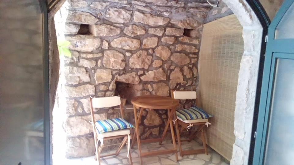 a table and two chairs in front of a stone wall at Calypso's Cave the Apartment for Animal Lovers in Babino Polje