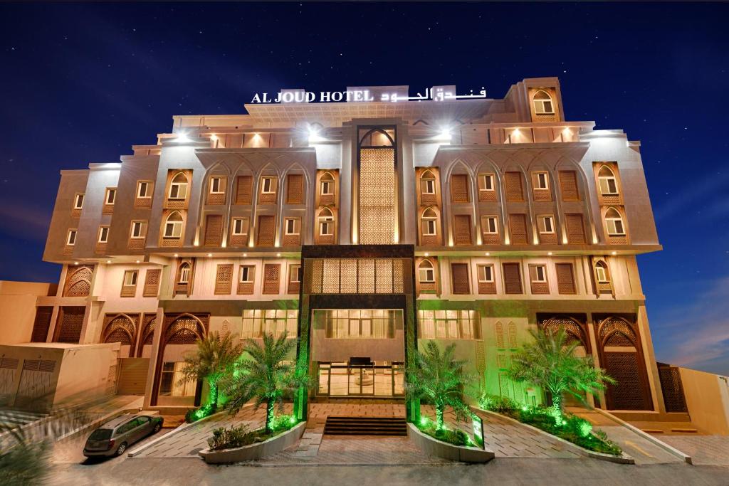 a large building with palm trees in front of it at Al Joud Hotel Makkah in Mecca