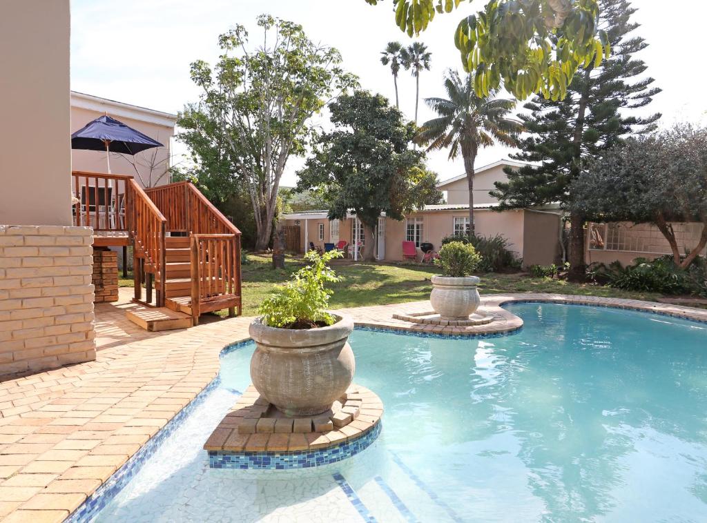 a swimming pool with two planters in a yard at Newington Place in Port Elizabeth