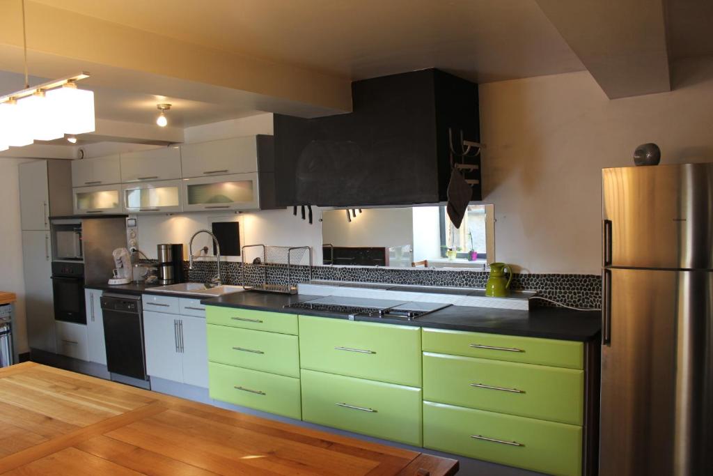 a kitchen with green cabinets and a stainless steel refrigerator at Gîte Orus in Orus