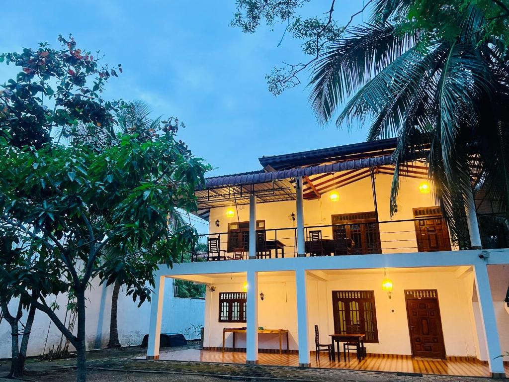a white house with a balcony and a table at Freedom Lodge Yala in Tissamaharama