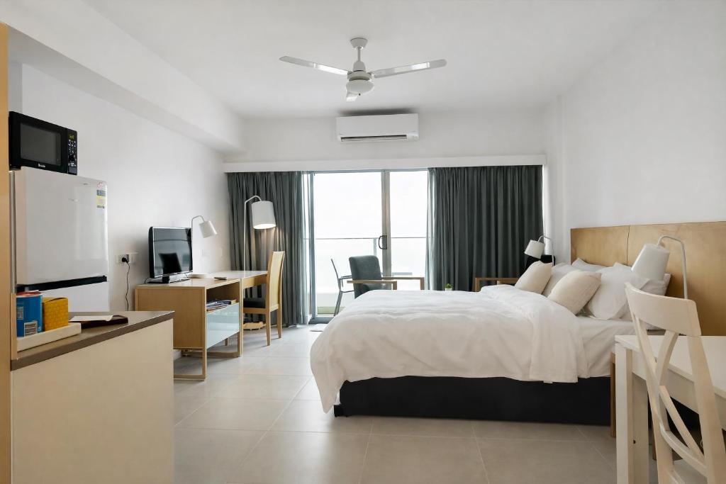 a hotel room with a bed and a desk and a television at Darwin Central Escape Hotel Style Apartment with Kitchen , Pool , Gym , Car Park,Balconey in Darwin