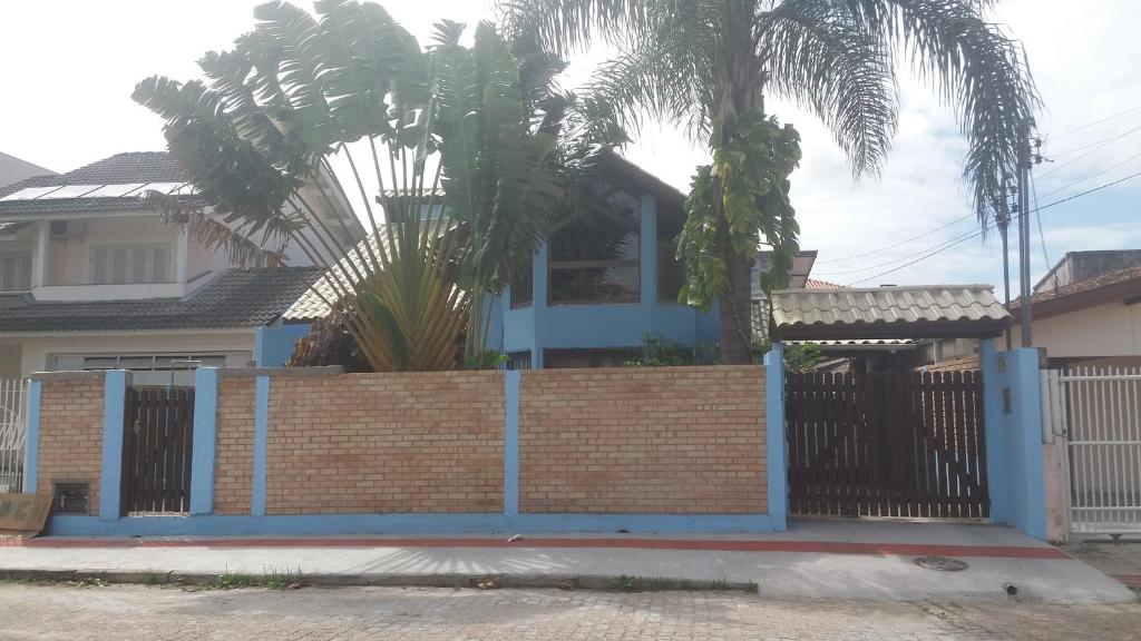 a brick fence with a blue gate in front of a house at Tartaruga Azul in Florianópolis